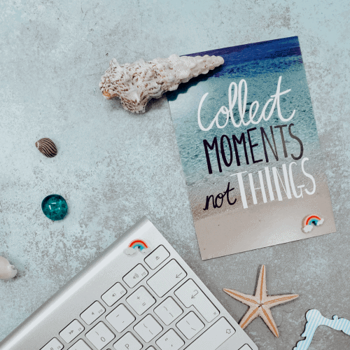 blue-faded-background-corner-of-mac-keyboard-colourful-shells-with-postcard-with-quote-collect-moments-not-things