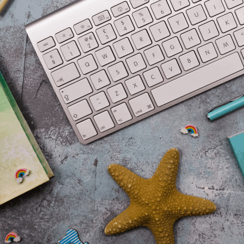 close-up-mac-keyboard-starfish-on-faded-blue-background-with-little-rainbow-stickers